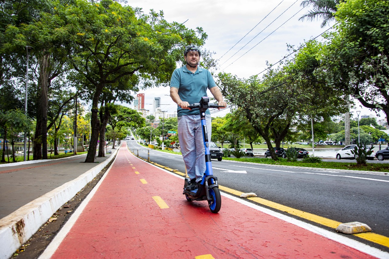 Usuário pilotando patinete elétrico JET em ciclovia arborizada